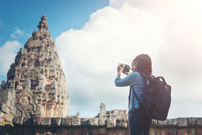 Rear view of man photographing against sky