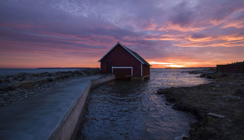 House by sea against sky during sunset