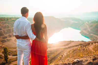 Rear view of couple standing on mountain against sky