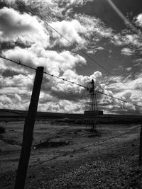 Electricity pylon on field against sky