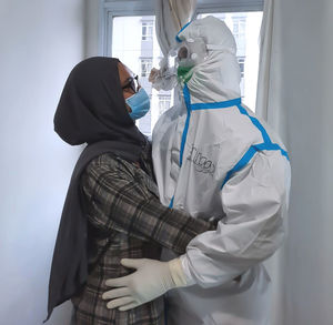 Side view of man holding woman standing against wall