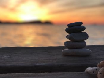 Stack of pebbles on shore against sea during sunset