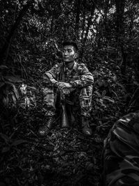 Thoughtful male army officer sitting in forest