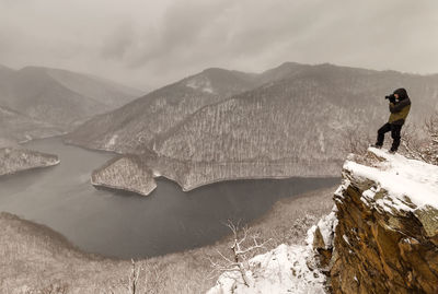 Man standing on snow covered mountain against sky