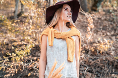 Young woman wearing hat standing against trees during autumn