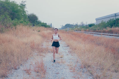 Full length portrait of young woman on land against sky