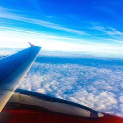 View of airplane wing over clouds