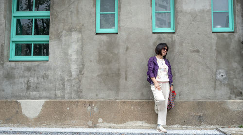 Full length of woman standing against building in city