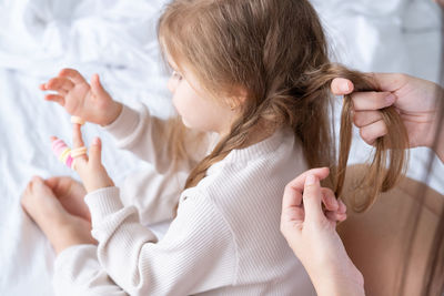 Cropped hand of mother tying daughters hair