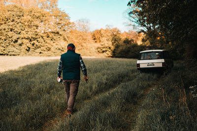 Rear view of man walking on dirt road