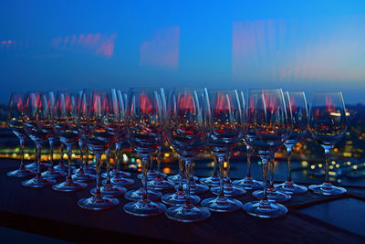 Wineglasses arranged on table against blue sky at sunset