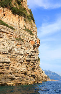 Scenic view of rocky mountains by sea against sky