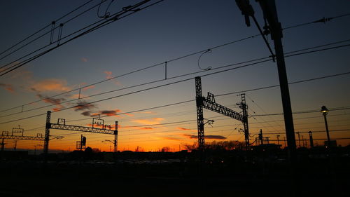 Silhouette electricity pylon against sky during sunset