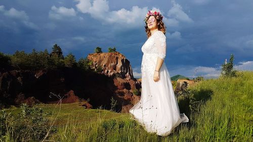 Woman standing on field against trees and sky