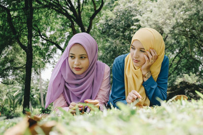 Female friends in hijab lying on field