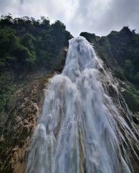 Scenic view of waterfall against sky