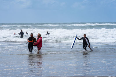 People enjoying on beach against sky