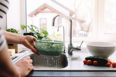 Woman washing green salad leaves for salad in kitchen in sink. high quality photo