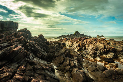 Rock formations on beach against sky