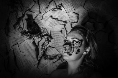 Woman with artificial butterfly looking at bird on burnt papers