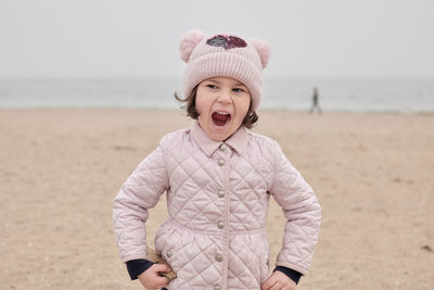 Young girl is playing on an empty beach during a foggy, cold day