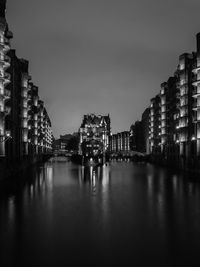 Canal amidst illuminated cityscape against sky at night