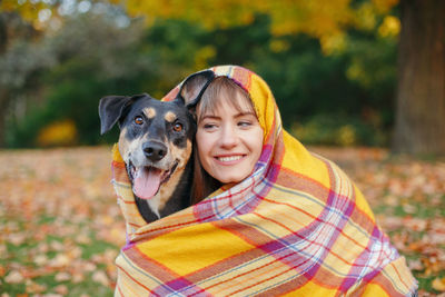 Smiling woman with dog during autumn