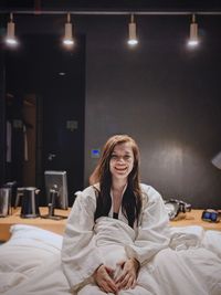 Portrait of smiling young woman sitting on bed