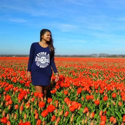 Young woman standing on field against sky