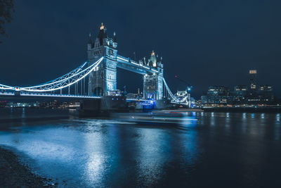 Illuminated bridge over river at night