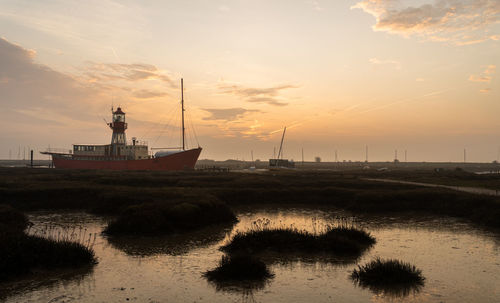 Sailboats moored on sea against sky during sunset