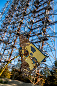 Low angle view of sign on tree against sky