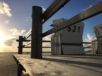 Hooded chairs on pier against sky at beach