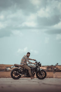 Man riding bicycle on road against sky