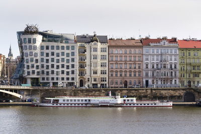 Buildings by river against clear sky