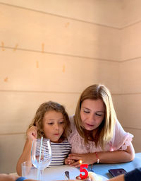 Portrait of mother and girl sitting on table