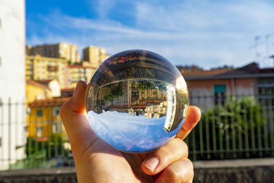 Close-up of person hand holding glass against sky