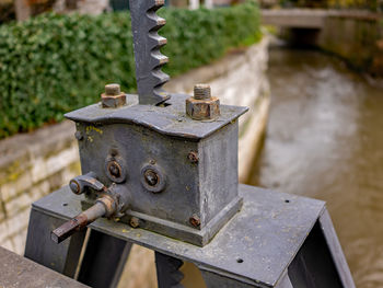 Close-up of rusty machine part by railing