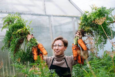 Portrait of young woman standing by plants