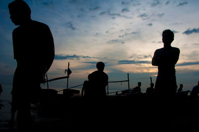 Silhouette man fishing at beach against sky during sunset