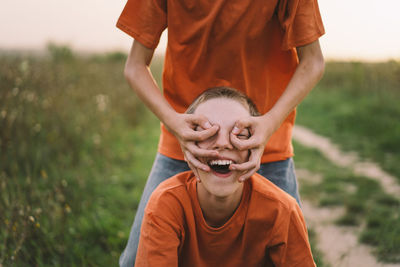 Funny twin brother boys playing outdoors on field at sunset.