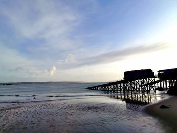 Pier over sea against sky during sunset