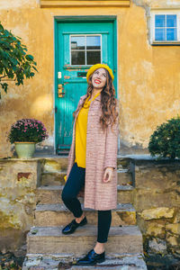 Portrait of young woman standing against brick wall