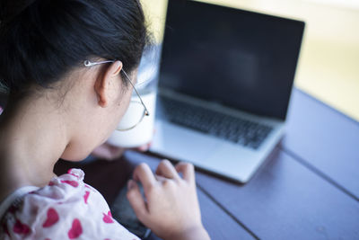 Close-up of woman using laptop at table