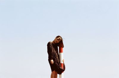 Young woman leaning on striped pole