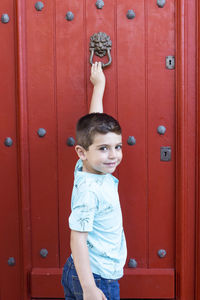 Portrait of boy standing against door