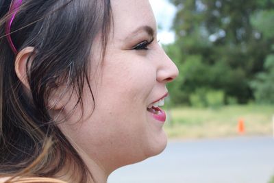 Close-up of young woman looking away while laughing outdoors