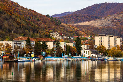 Sailboats in city by buildings against sky