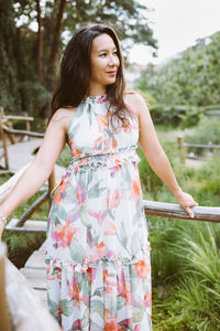 Happy multiracial japanese woman in romantic floral maxi dress in park