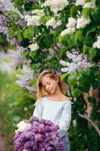 Portrait of young woman standing amidst plants